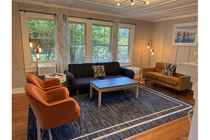 Living room with wood finished floors, healthy amount of natural light, a chandelier, and ornamental molding