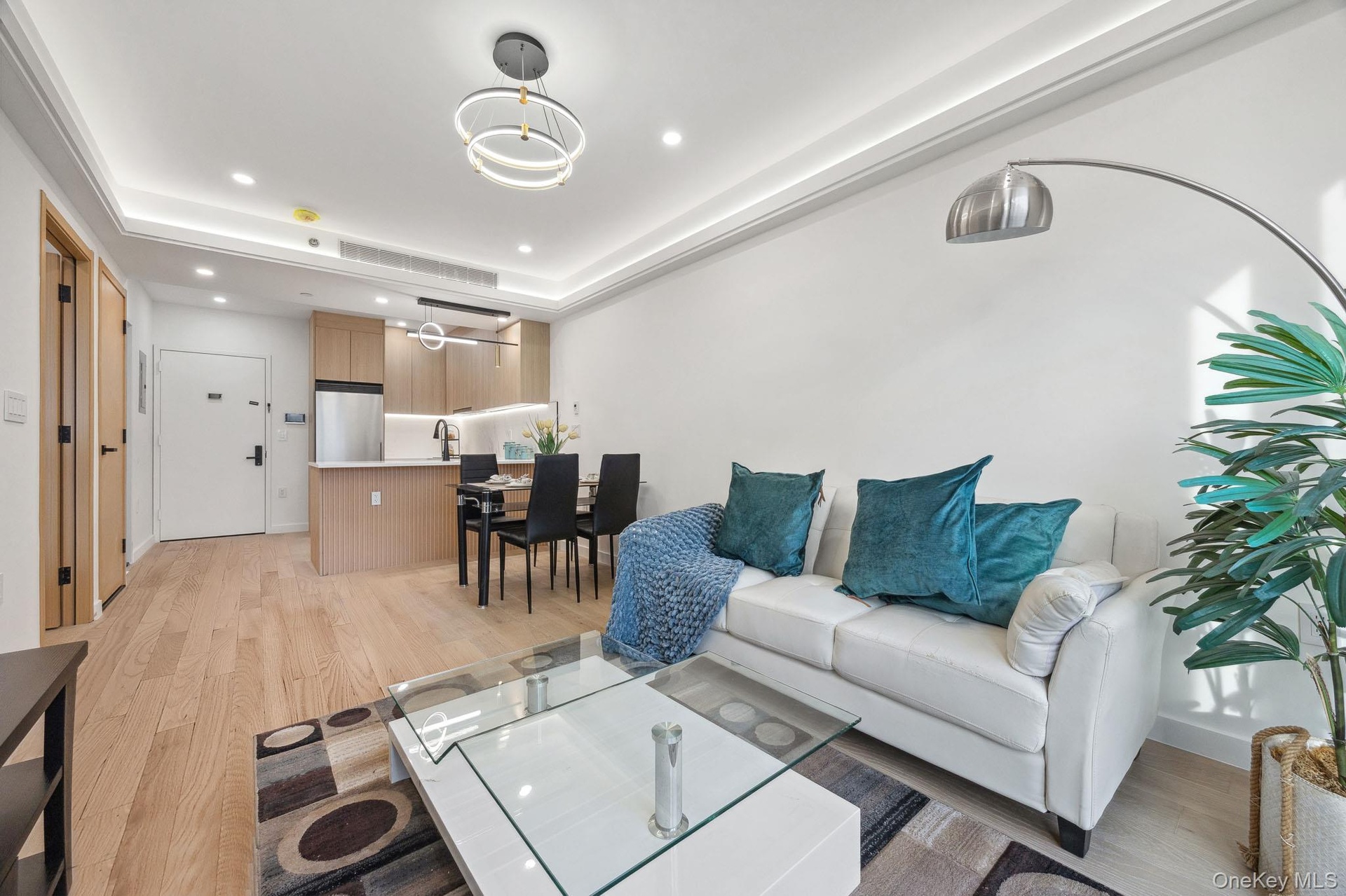 Living room with light wood-style flooring, recessed lighting, a raised ceiling, and a chandelier