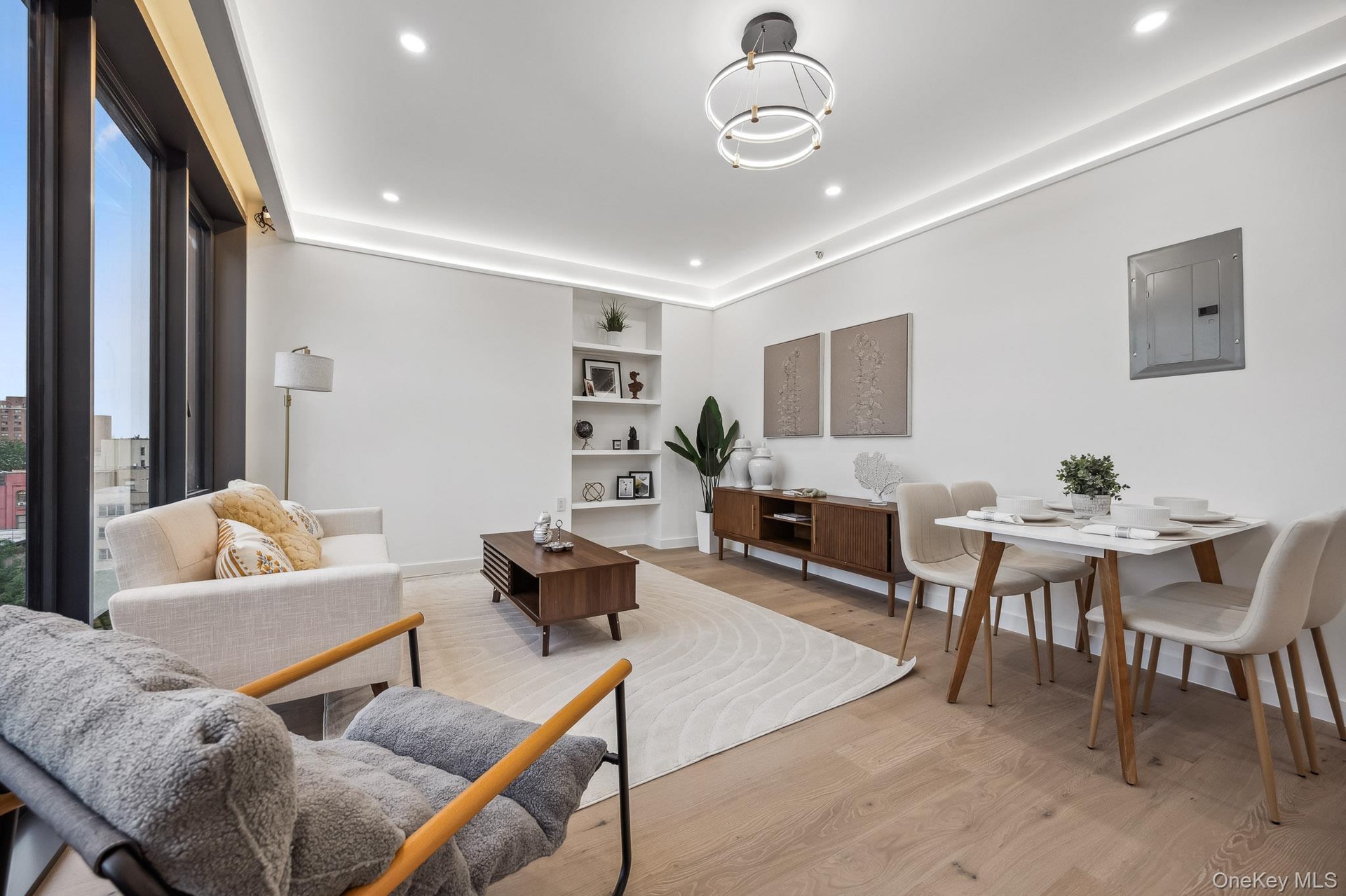 Living room with electric panel, light wood-type flooring, recessed lighting, baseboards, and built in shelves