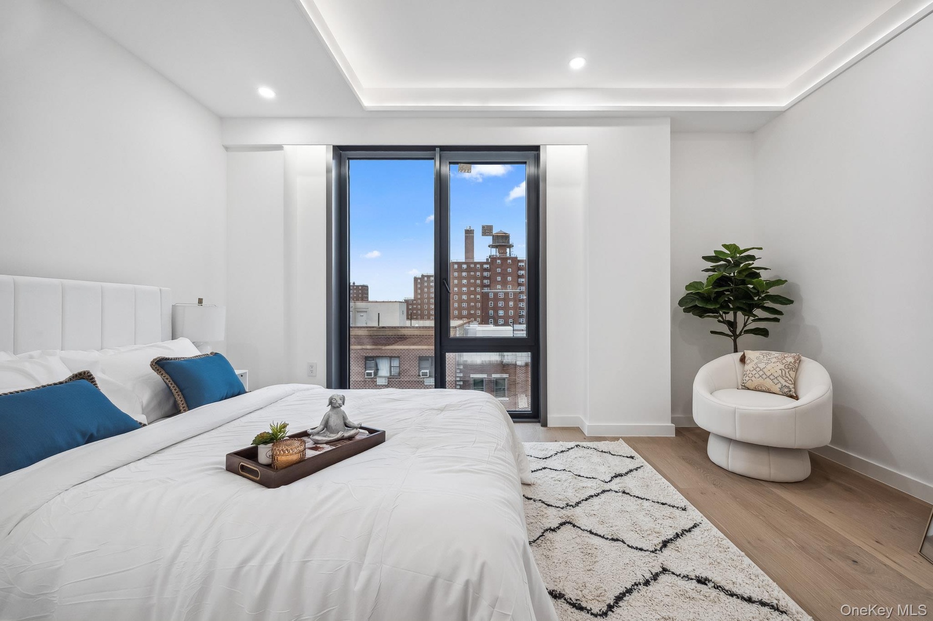 Bedroom with light wood-style flooring, baseboards, a city view, and recessed lighting