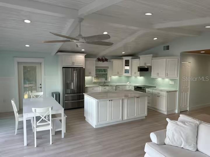 Open living area with a vaulted white wood ceiling and exposed trusses.