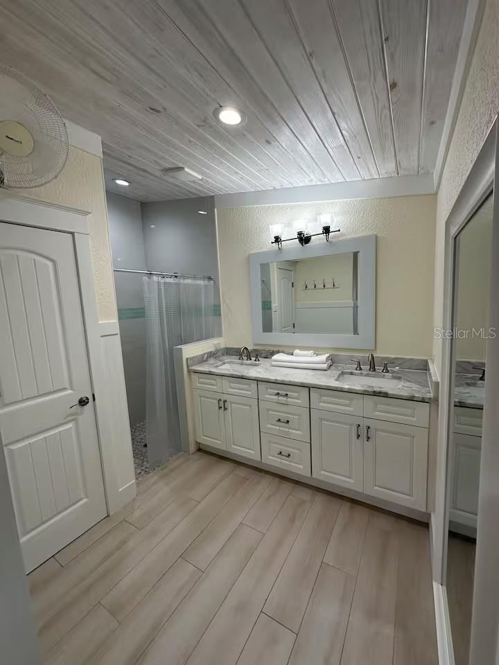 Master bathroom features timeless fixtures, a separate toliet room, a large vanity with double sinks, and a spacious walk-in shower. Soft lighting and