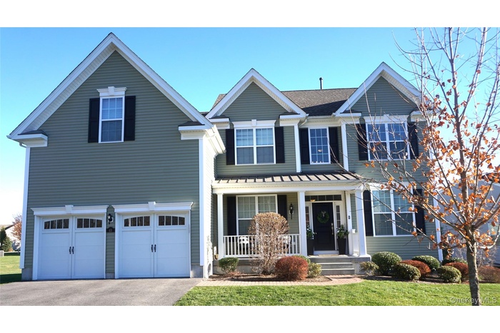 Traditional-style home featuring a porch, an attached 2 car garage, driveway, and a front yard