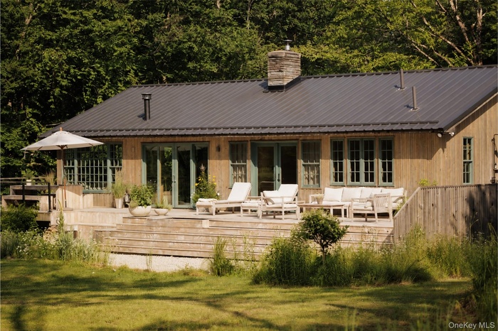 Back of house with 1150 sq ft deck overlooking the landscaped property, paths and Shandelee Brook.