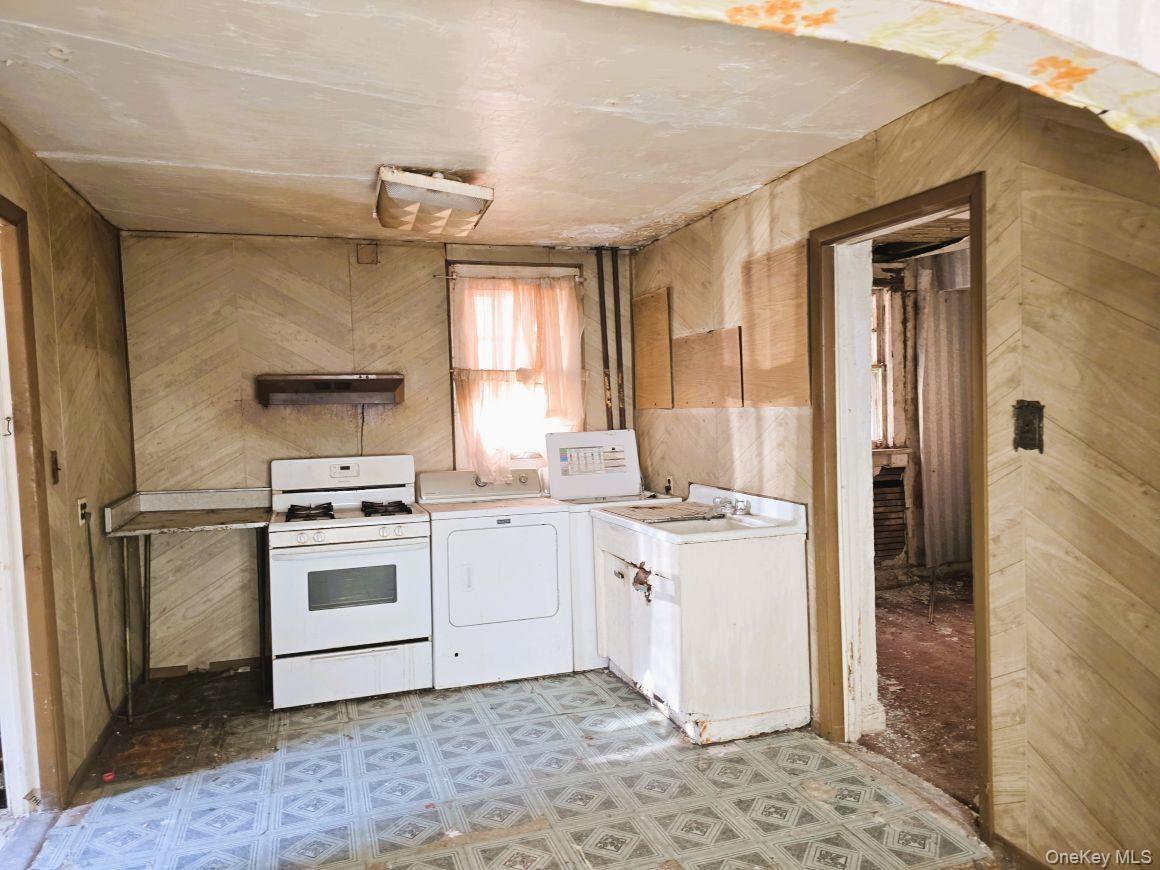 Kitchen space featuring patterned linoleum flooring and wood-look wall paneling