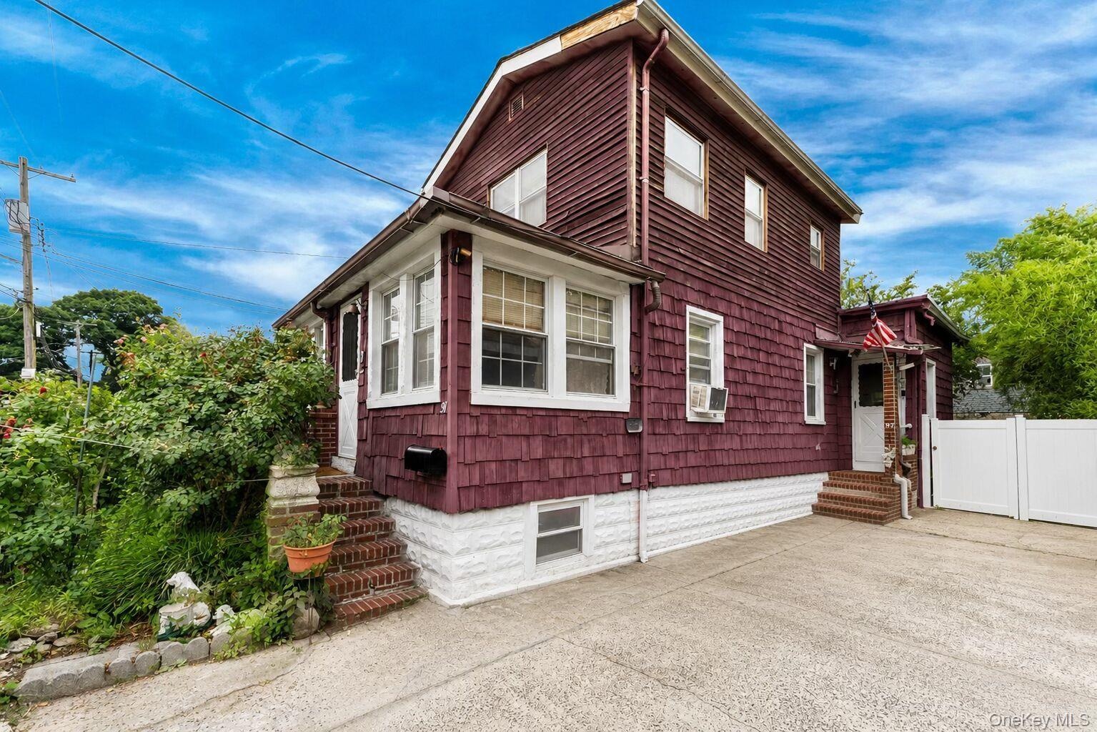 Two-story residence featuring deep red shingle and horizontal siding, white trim, and multiple windows