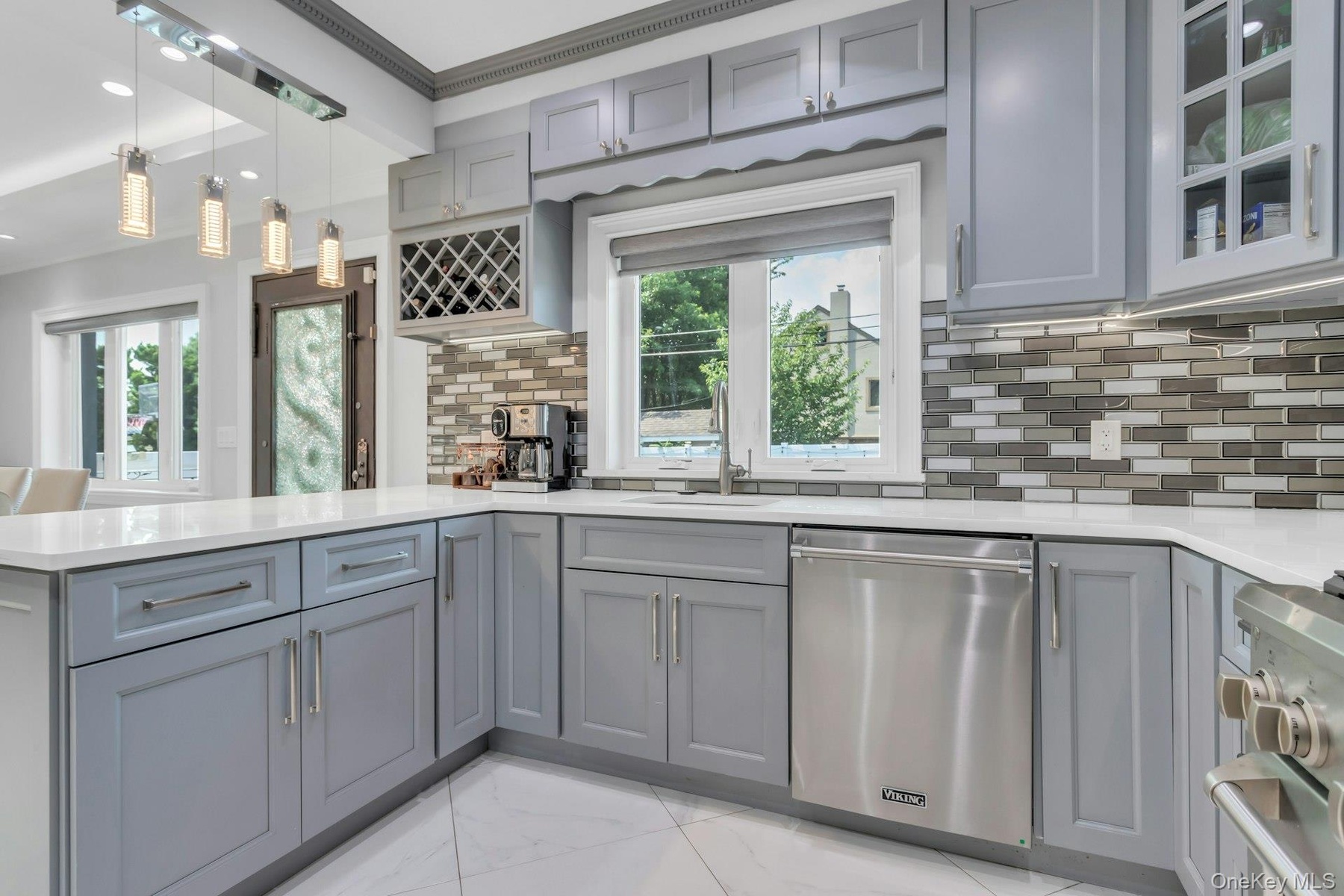 Contemporary kitchen featuring light gray cabinetry, white quartz countertops, undermount lighting, coutner seating