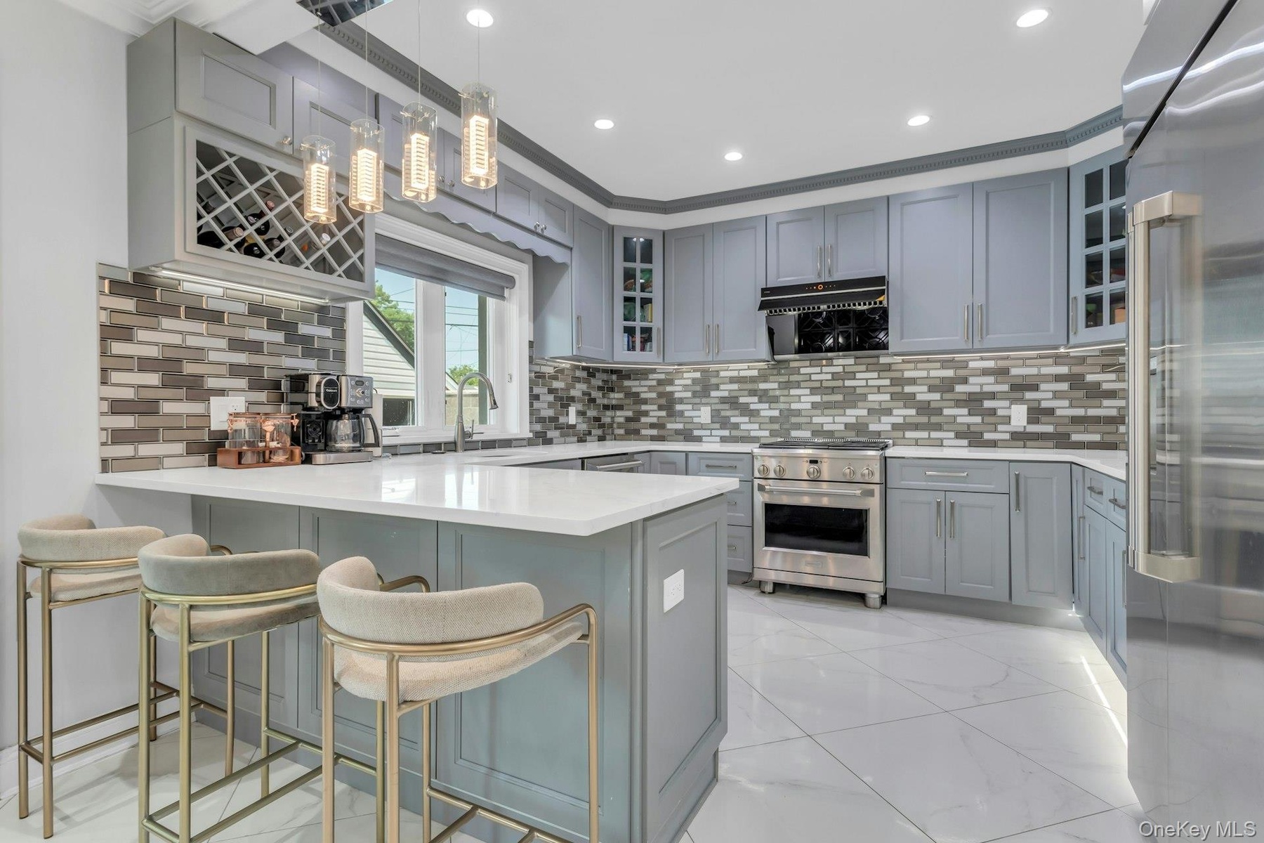 Custom cabinetry with integrated wine rack, stainless steel top of the line appliances, white quartz countertops, over-sized porcelain tile flooring, 