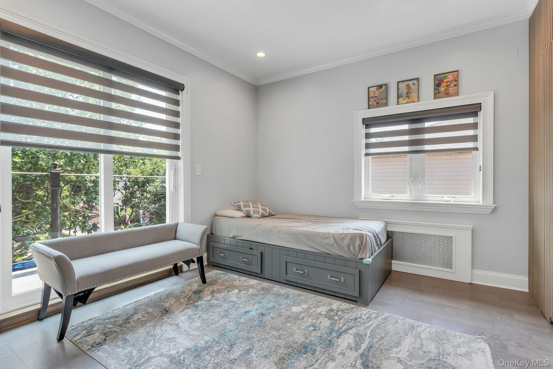 Room featuring wood-finish flooring, light grey walls, and white crown molding.