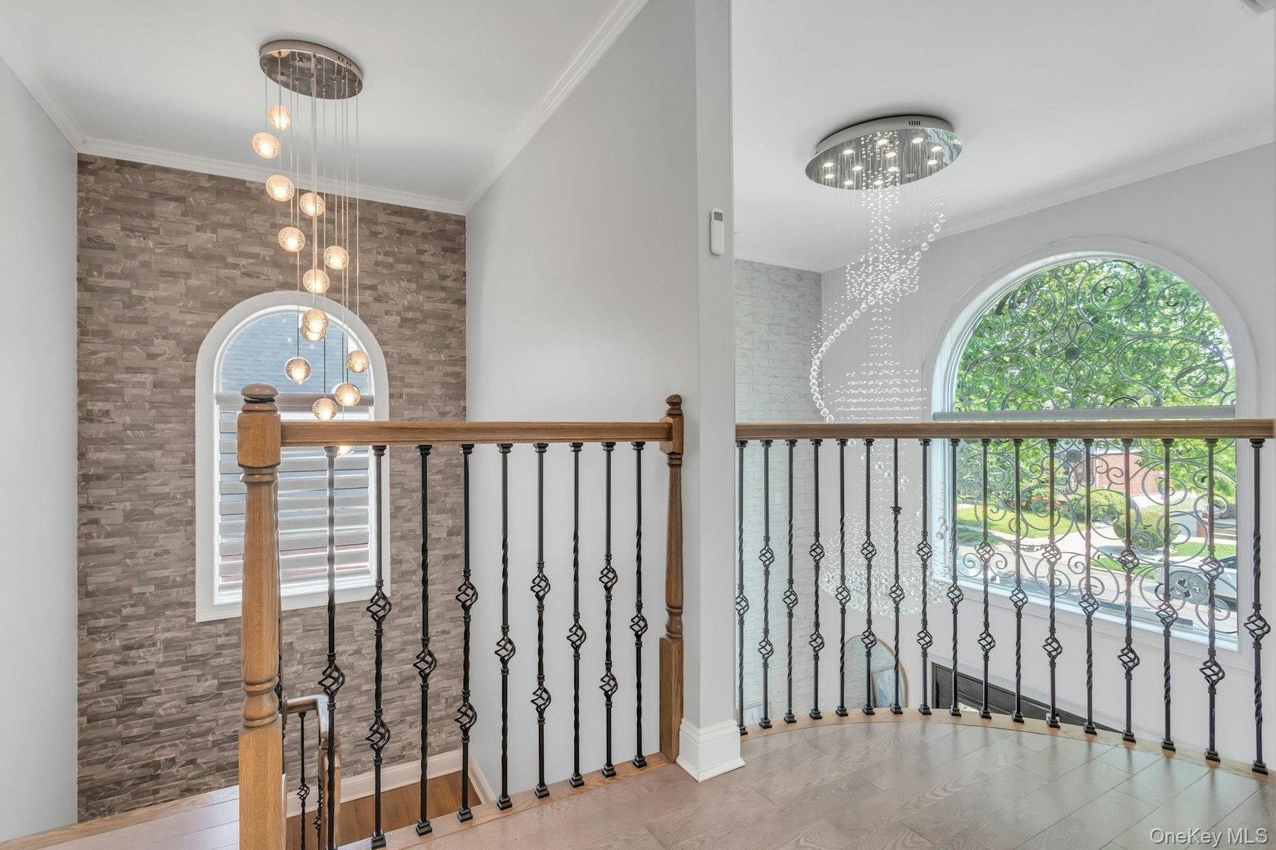 2nd story entry view, Stacked stone accent wall,Custom wood and decorative iron railing, glass chandelier, front pictureseque elliptical window adding