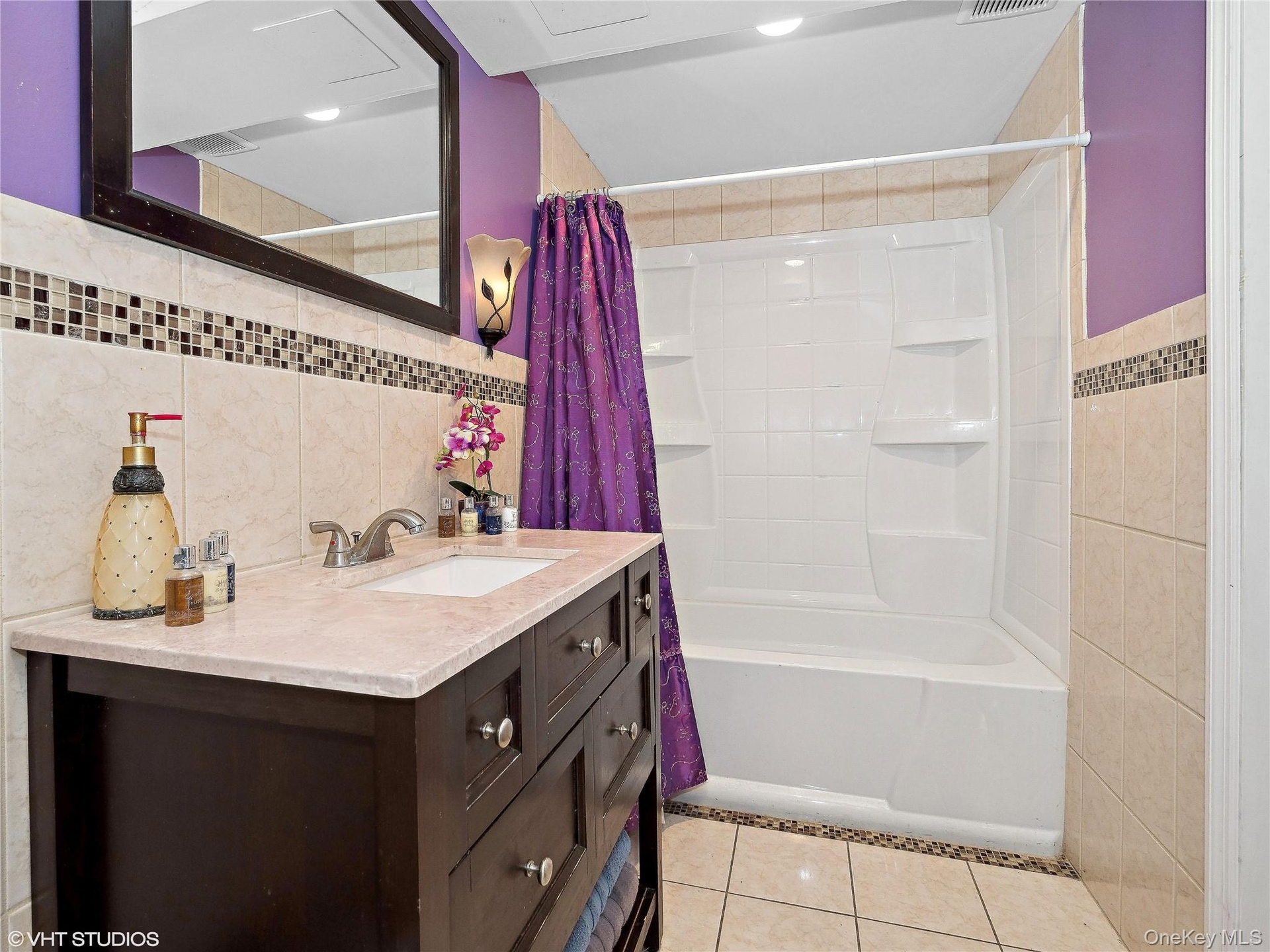 Bathroom featuring tile patterned floors, vanity, tile walls, and shower / tub combo with curtain