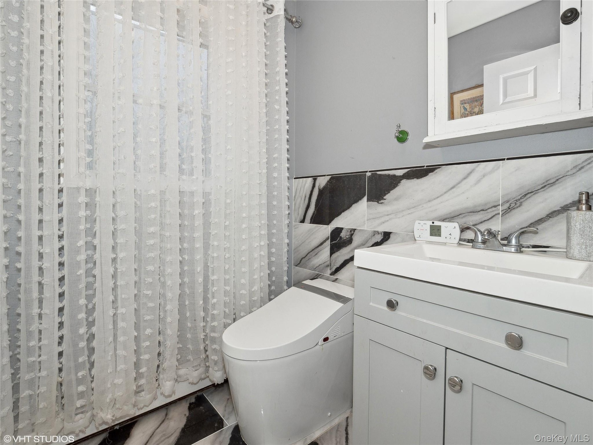 Bathroom featuring vanity, tile walls, and toilet