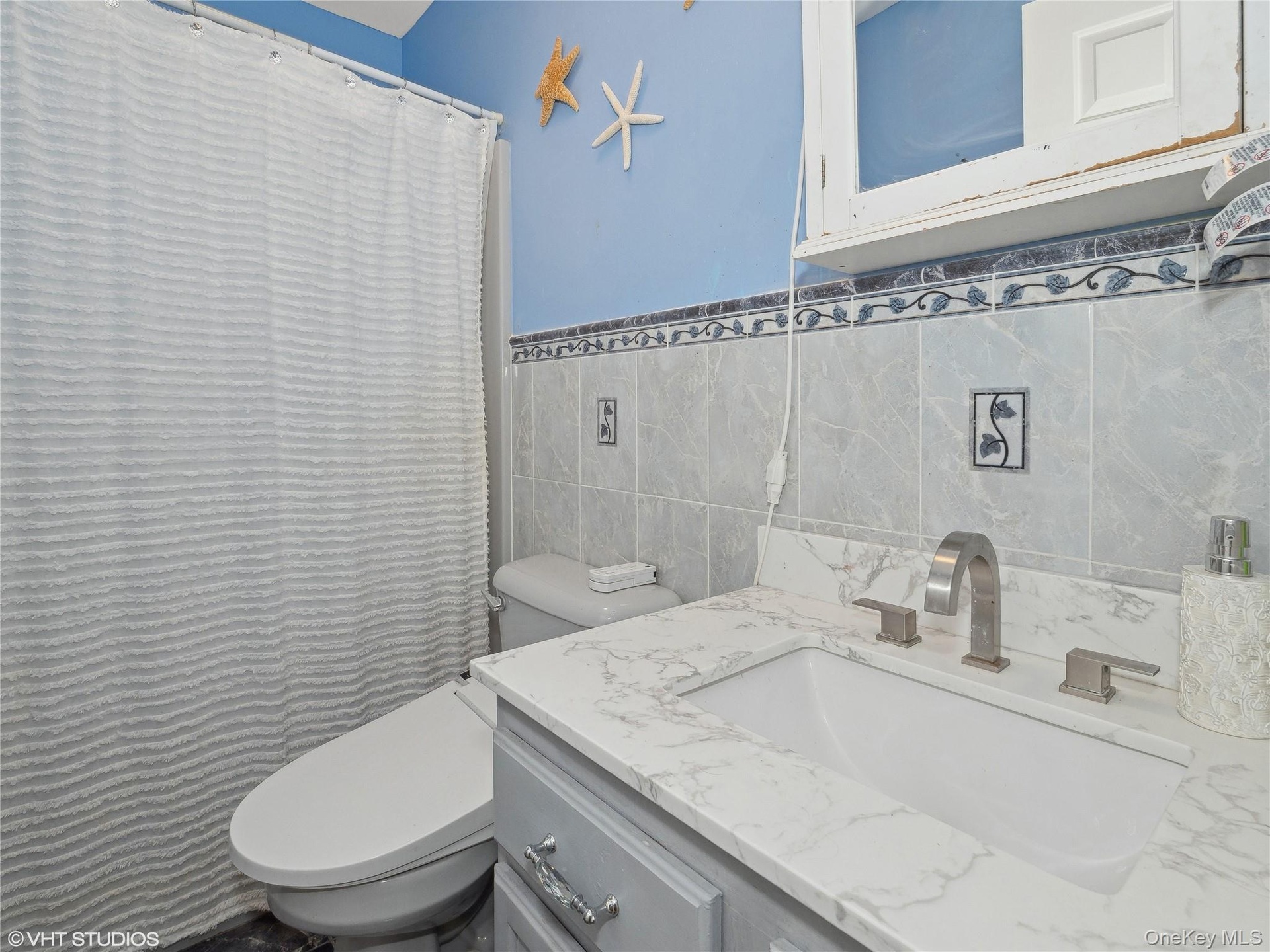 Bathroom featuring vanity, toilet, and tile walls
