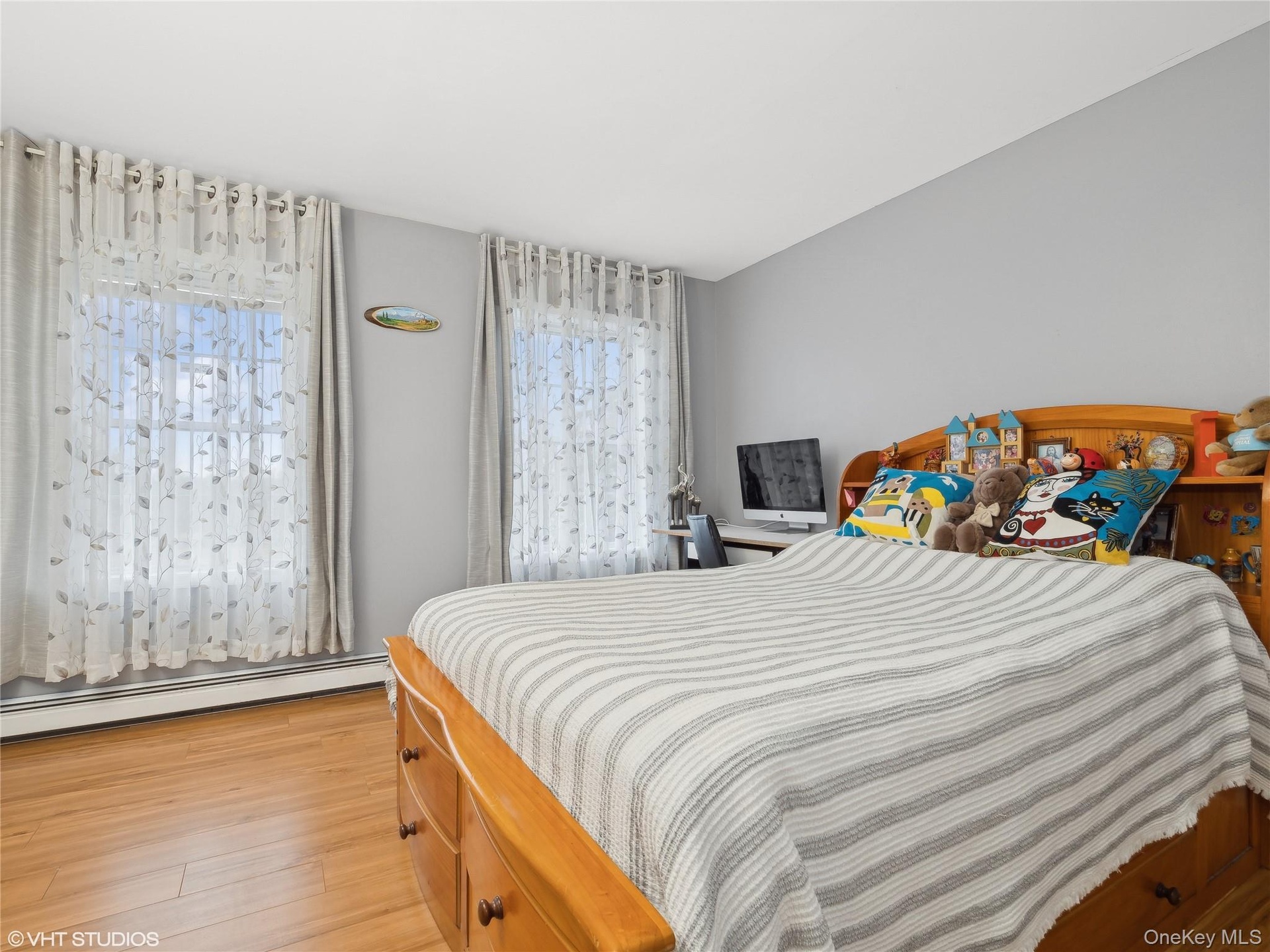 Bedroom featuring a baseboard radiator, light hardwood / wood-style flooring, and multiple windows