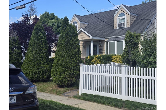 Traditional residence featuring dormer windows, a bay window, and a white picket fence