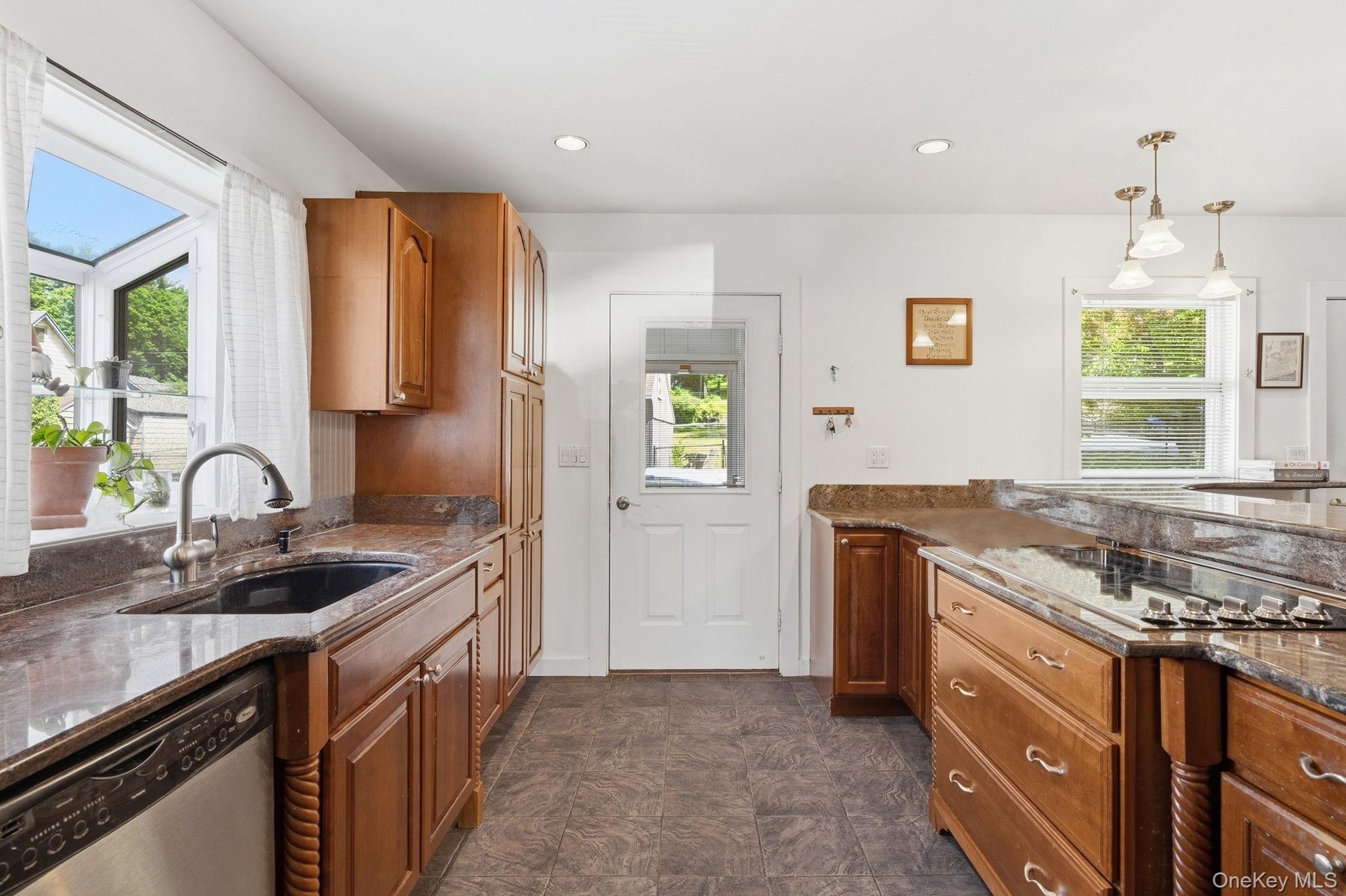 The heart of the home, offering abundant granite workspace, island seating, cherry cabinetry, a coffee station, stainless steel appliances, and storag