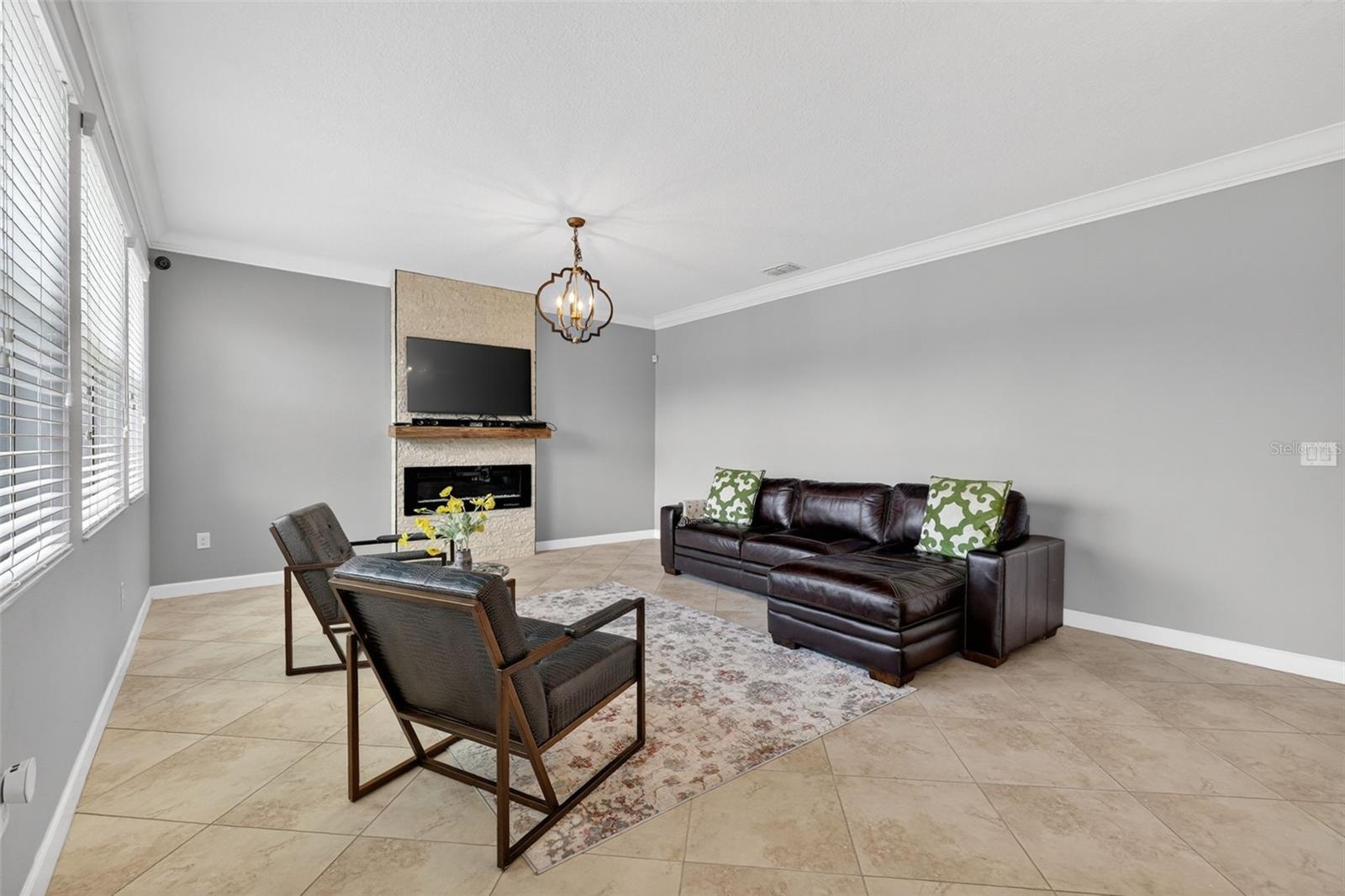 Living Room with Crown Molding, 3 Stunning Windows, Accent Wall with Stone Accent and Chandelier.