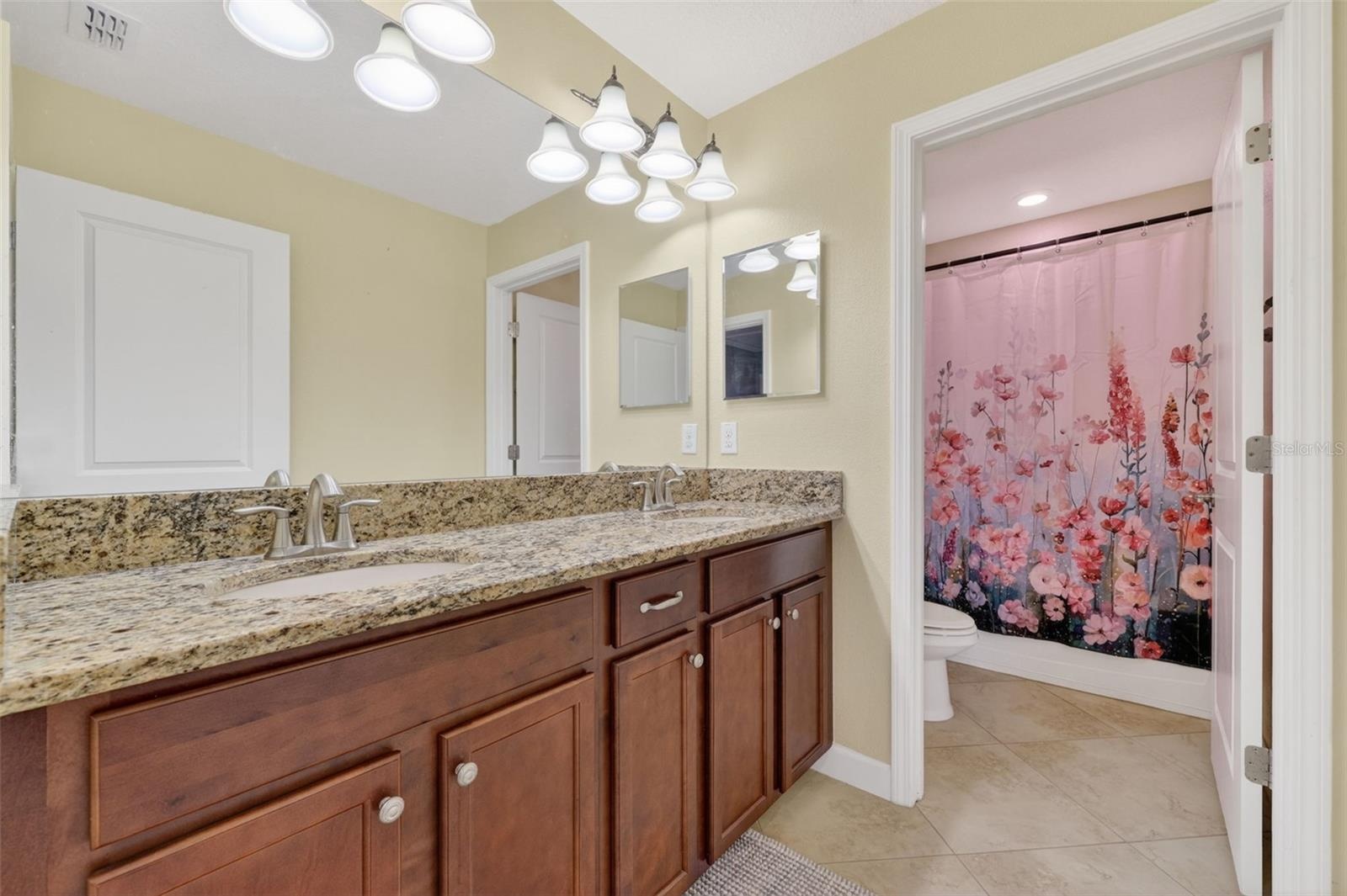Full Bathroom with Dual Vanities, Granite Countertops, and Shower/Tub Combination.