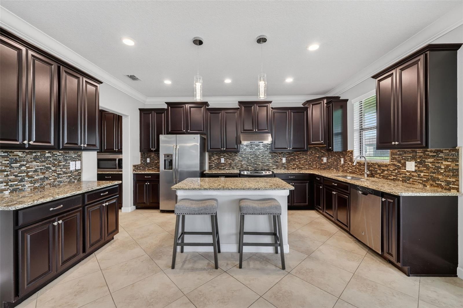 Full Gourmet Kitchen with Crown Molding, Island, Pendant & Recessed Lighting, Abundant Cabinets with Crown Trim, Granite Countertops, Backsplash, GE S