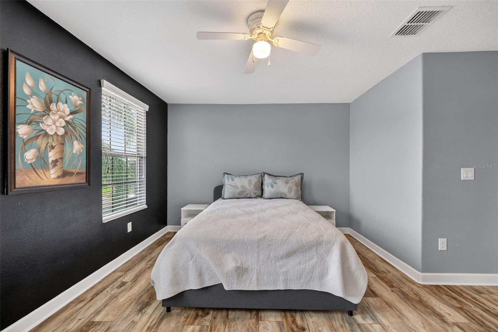 Bedroom #2 with LVP Flooring, Ceiling Fan, Walk-In Closet and Windows Overlooking the Front of the Home.