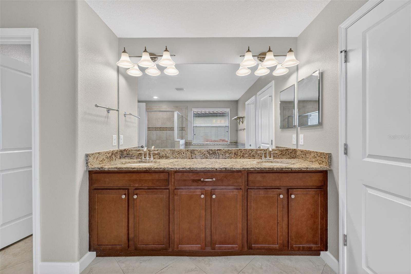 Primary En-Suite Bathroom with Dual Vanities, Granite Countertops, Garden Soaking Tub with Window, Shower Stall with Glass Frame, Private Water Closet