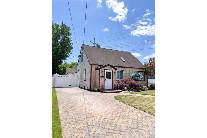 Exterior featuring shingle siding, a multi-tone paver driveway, and a fenced yard