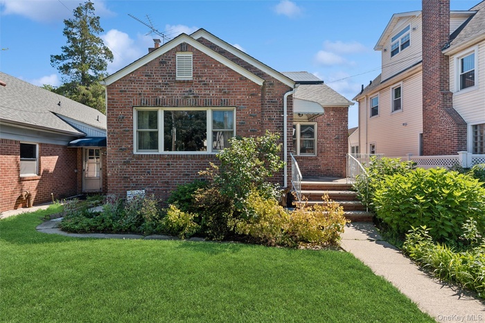 Brick exterior with a gabled roofline, multiple windows, and a paved walkway leading to the entrance
