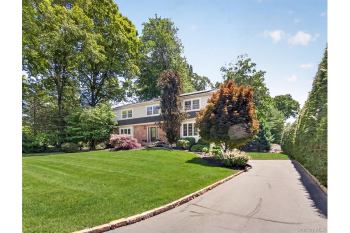 An impressive approach reveals this stately Colonial, nestled among mature trees and meticulous landscaping.