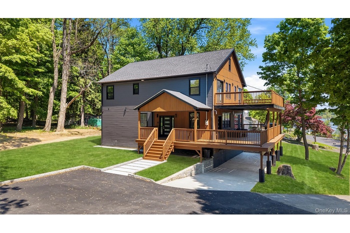 Modern multi-level residence featuring dark siding, natural wood accents, and a tiered deck system