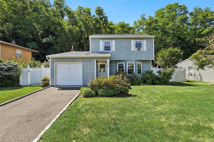 Two-story residence featuring light blue siding with white trim, a one-car garage, and a paved driveway with stone border