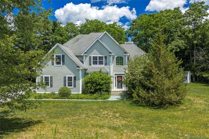 Two-story residence featuring light gray siding with dark shutters, multiple gables, and a prominent front entry with an arched window above