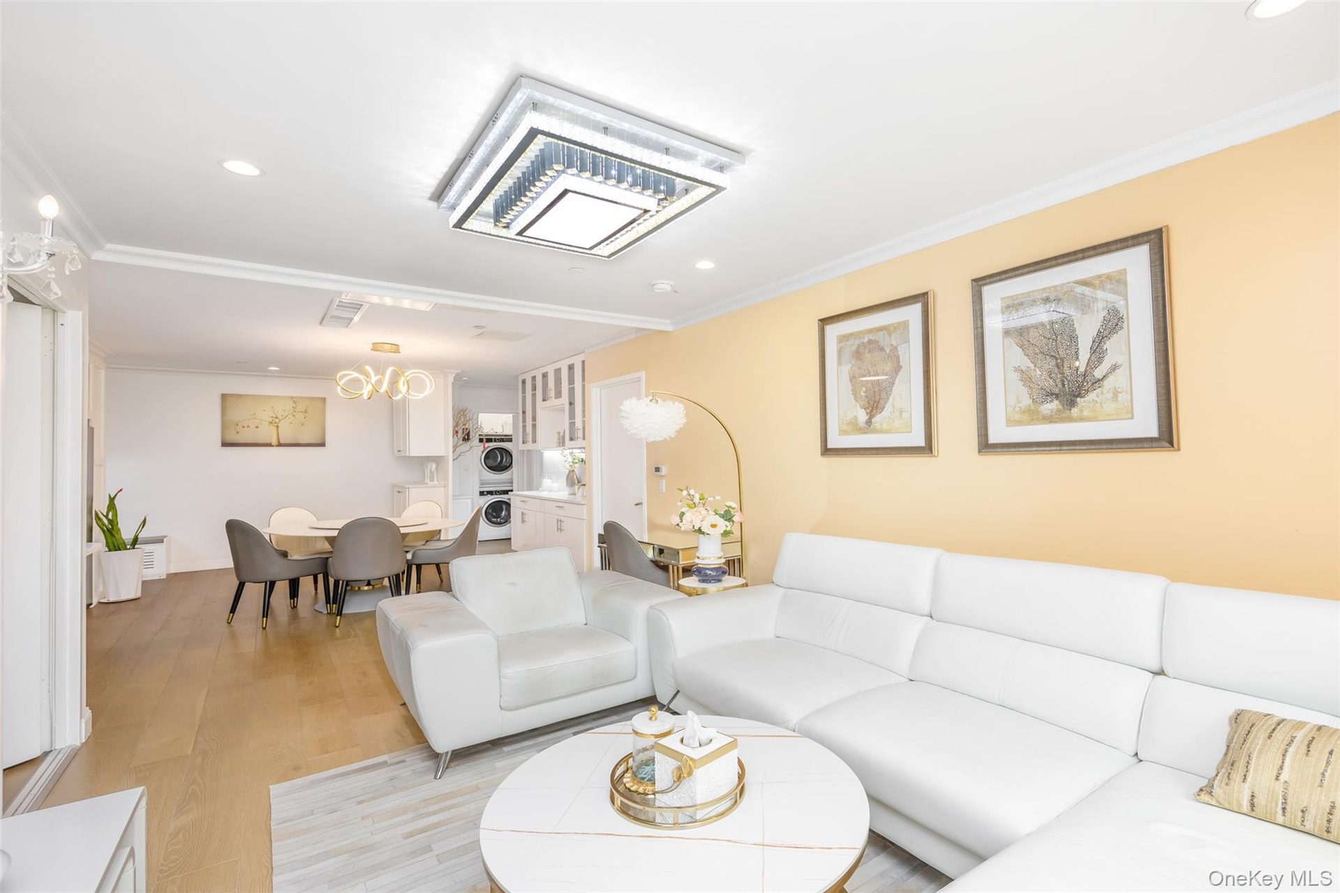 Living room featuring recessed lighting, ornamental molding, wood finished floors, and stacked washer / dryer