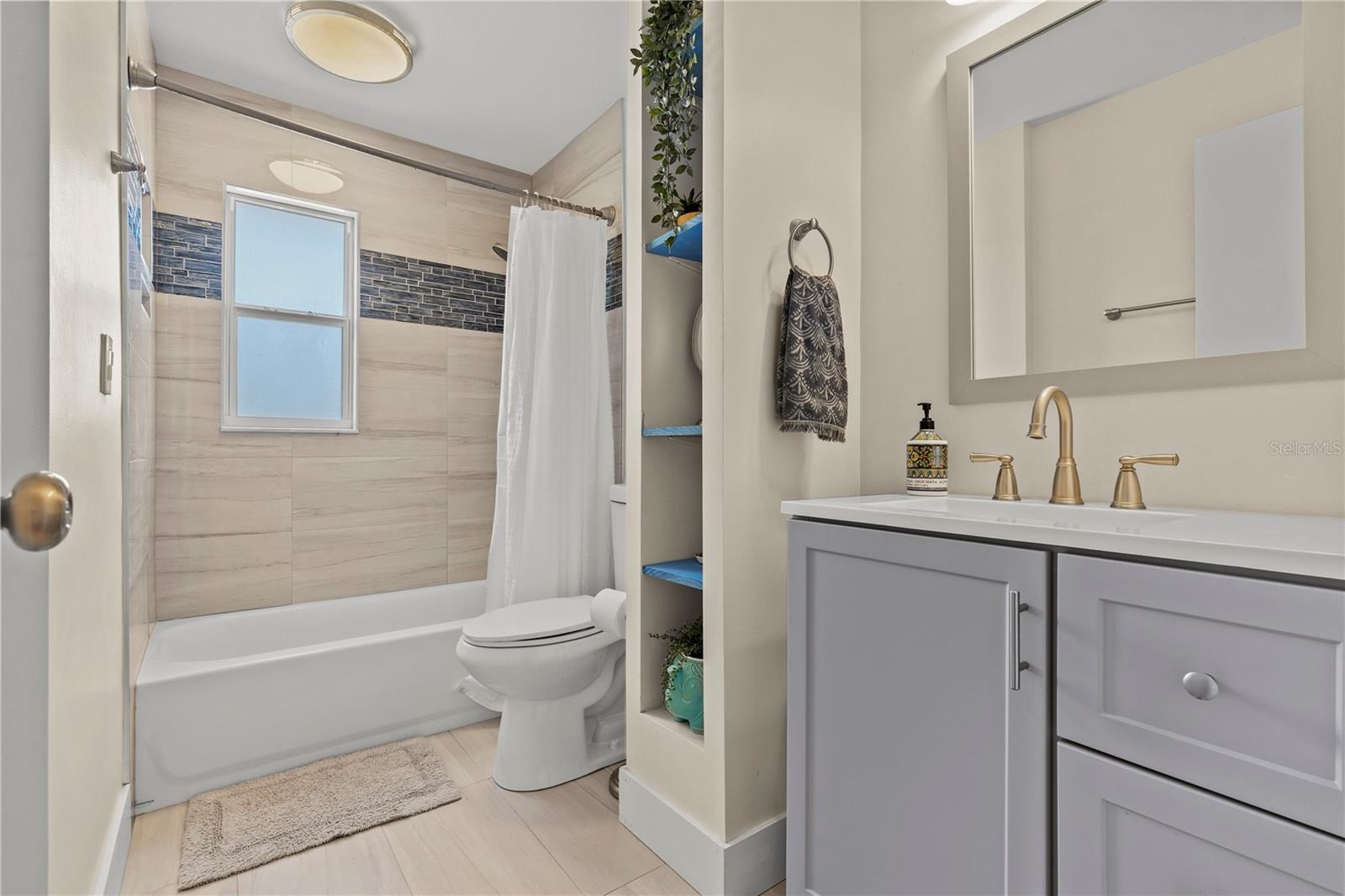 Hall bathroom with updated tile and vanity. Tub shower combo.