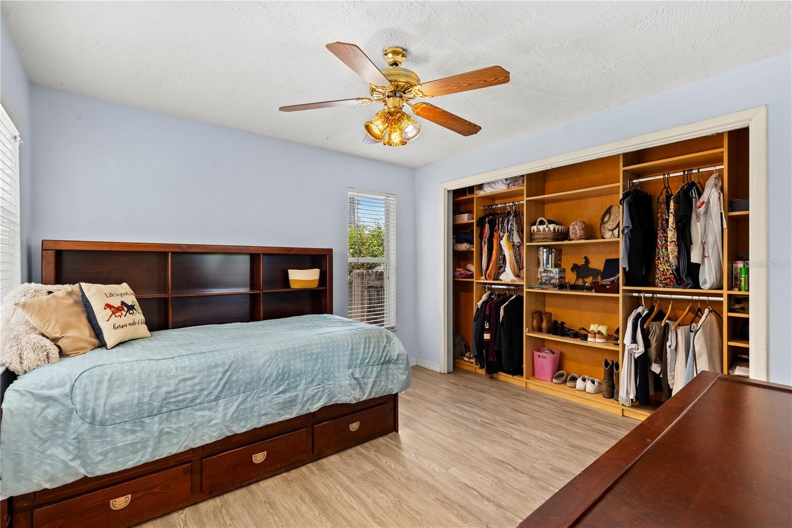 Well-appointed second bedroom featuring abundant natural light and a custom closet organizer designed to maximize storage and keep everything neatly a