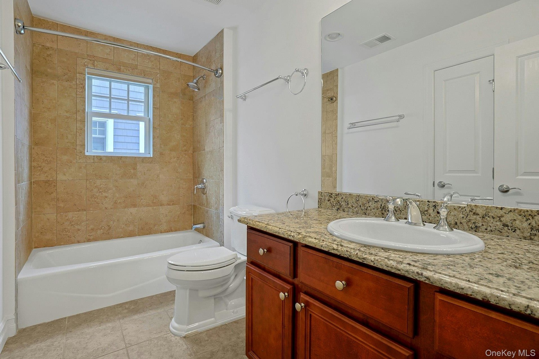 The beautifully appointed hall bath features a granite-topped vanity, warm stone tile, and a full tub/shower combination, blending style and functiona