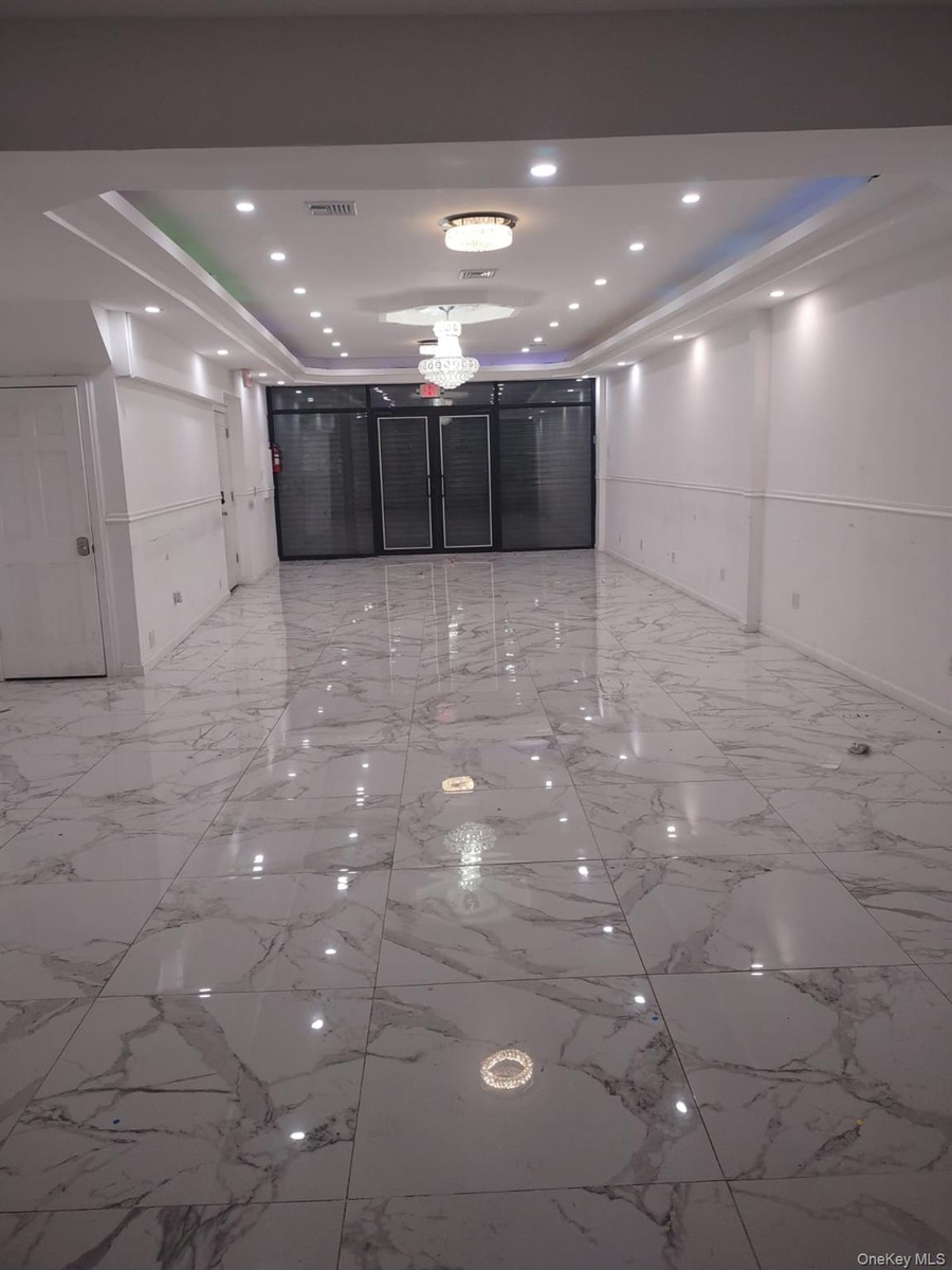 Spare room with a raised ceiling, light marble finish flooring, and recessed lighting