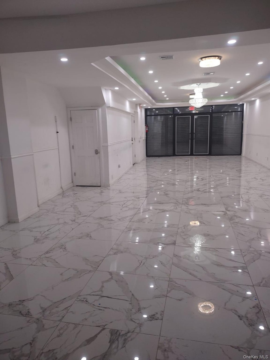 Corridor with light marble finish floors, recessed lighting, and a raised ceiling