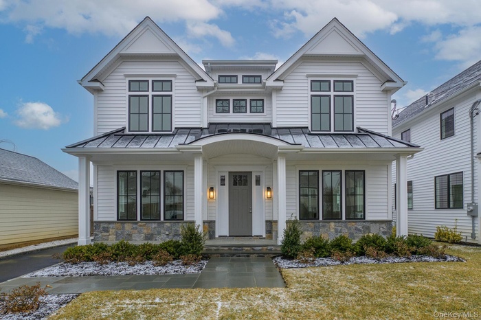 View of front of home featuring stone siding, a standing seam roof, covered porch, and metal roof