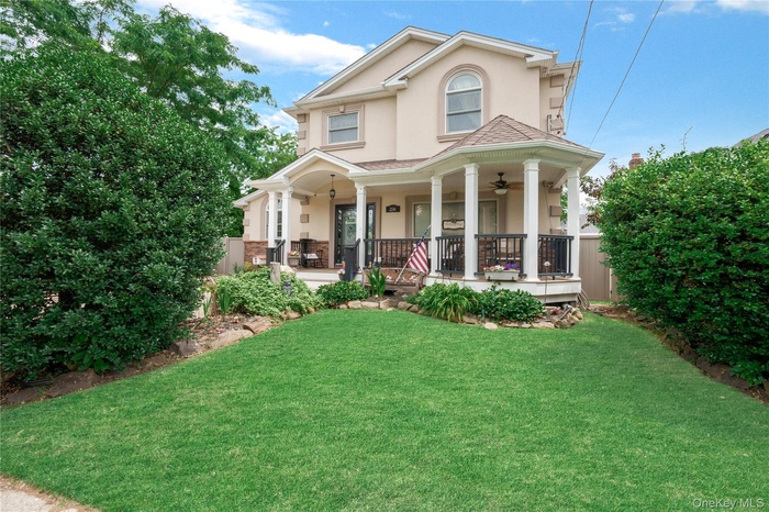 Stucco exterior with a columned porch featuring a ceiling fan and wrought iron railing