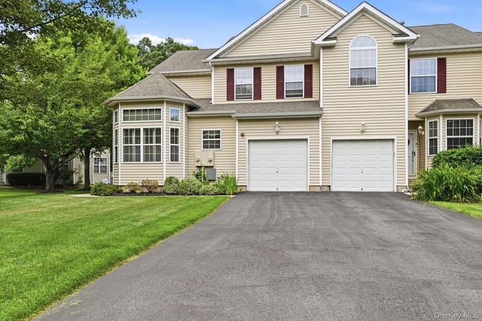 Light beige siding exterior with a one-car garage, red window shutters, a prominent bay window, and a paved driveway
