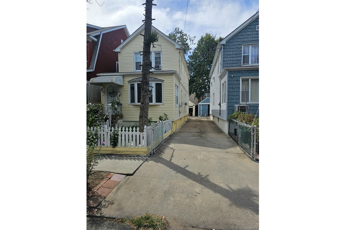 Yellow siding two-story residence featuring a bay window and an awning over the front entry
