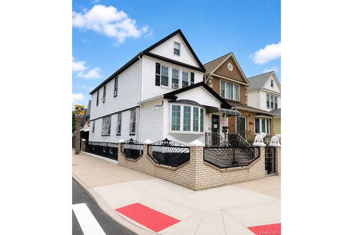 White siding exterior with a prominent bay window, contrasting black trim, and a gabled roofline