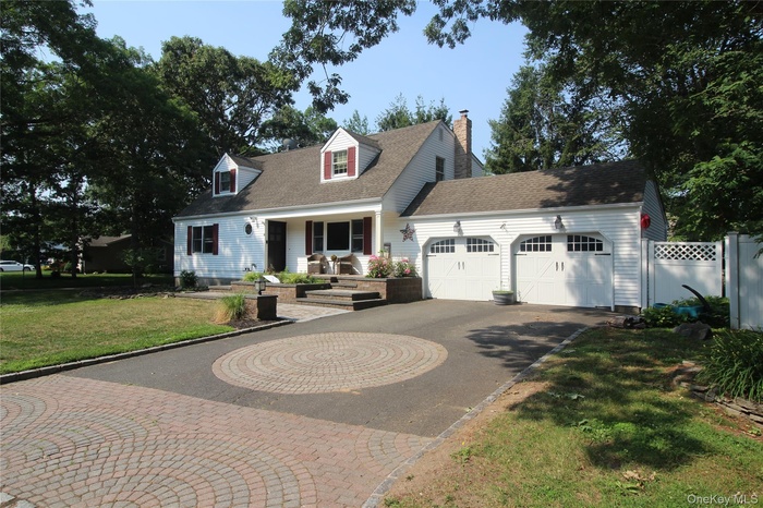 White siding residence featuring a two-car garage with arched panel doors and overhead lighting. Architectural Driveway.