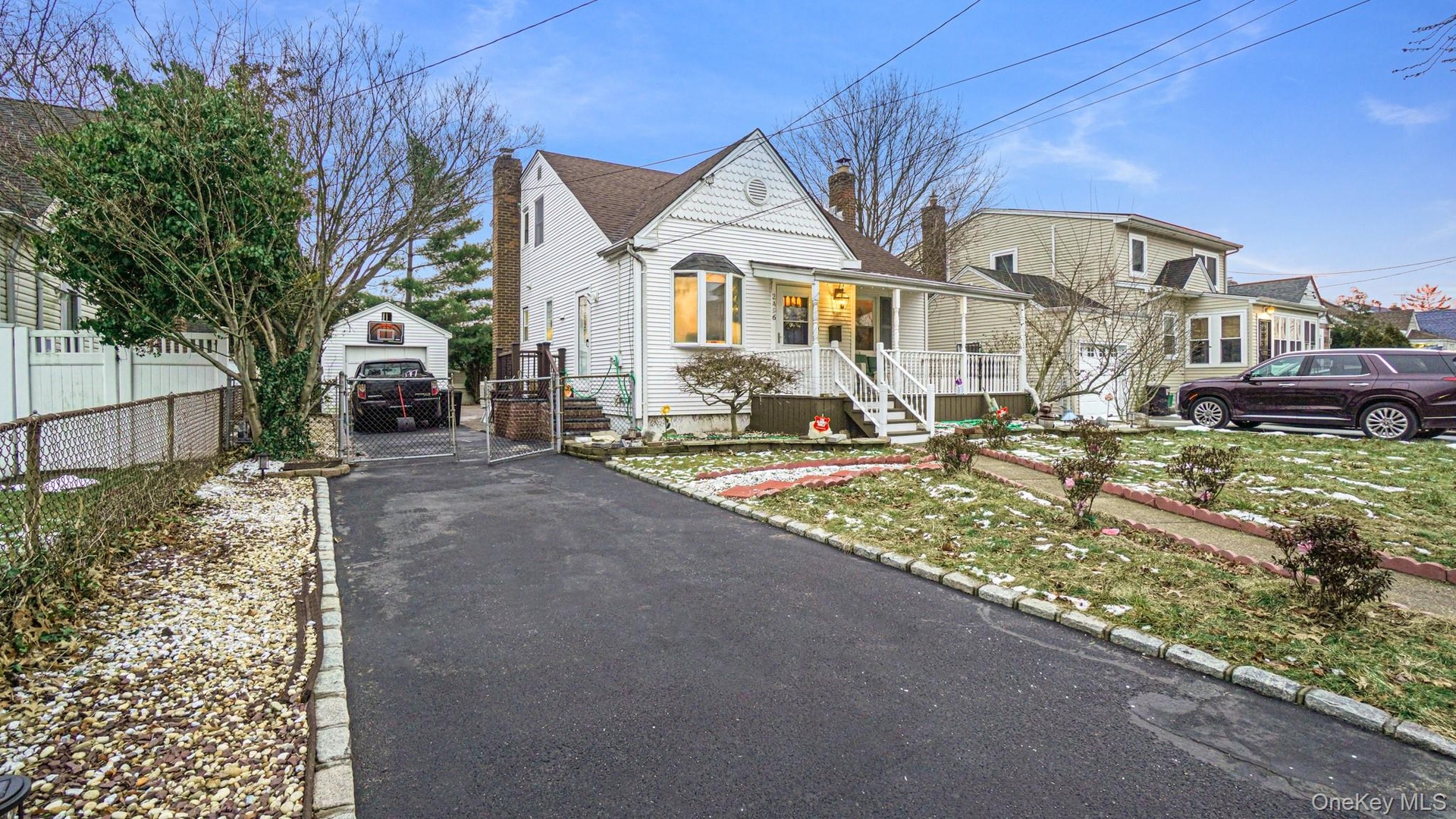 View of front of home with a gate, a chimney, driveway, covered porch, and fence