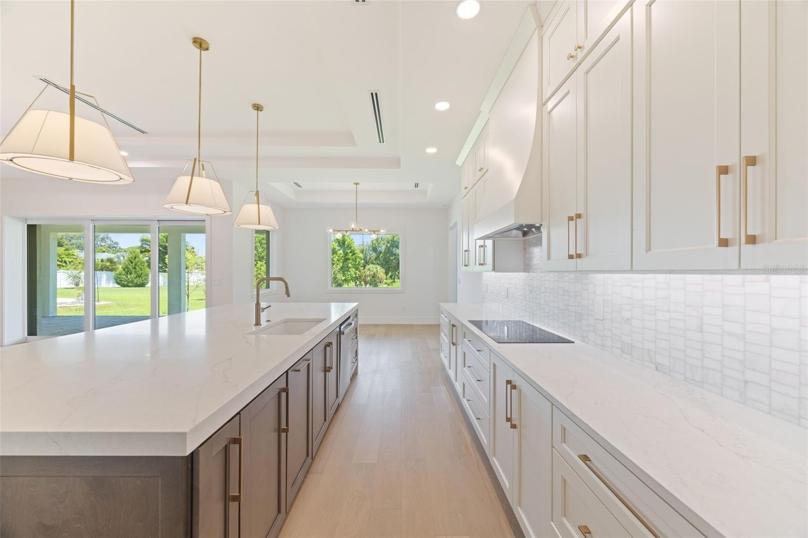 The gourmet kitchen is a true showpiece, featuring full-height custom cabinetry, an oversized 11-foot quartz island with storage on both sides, marble