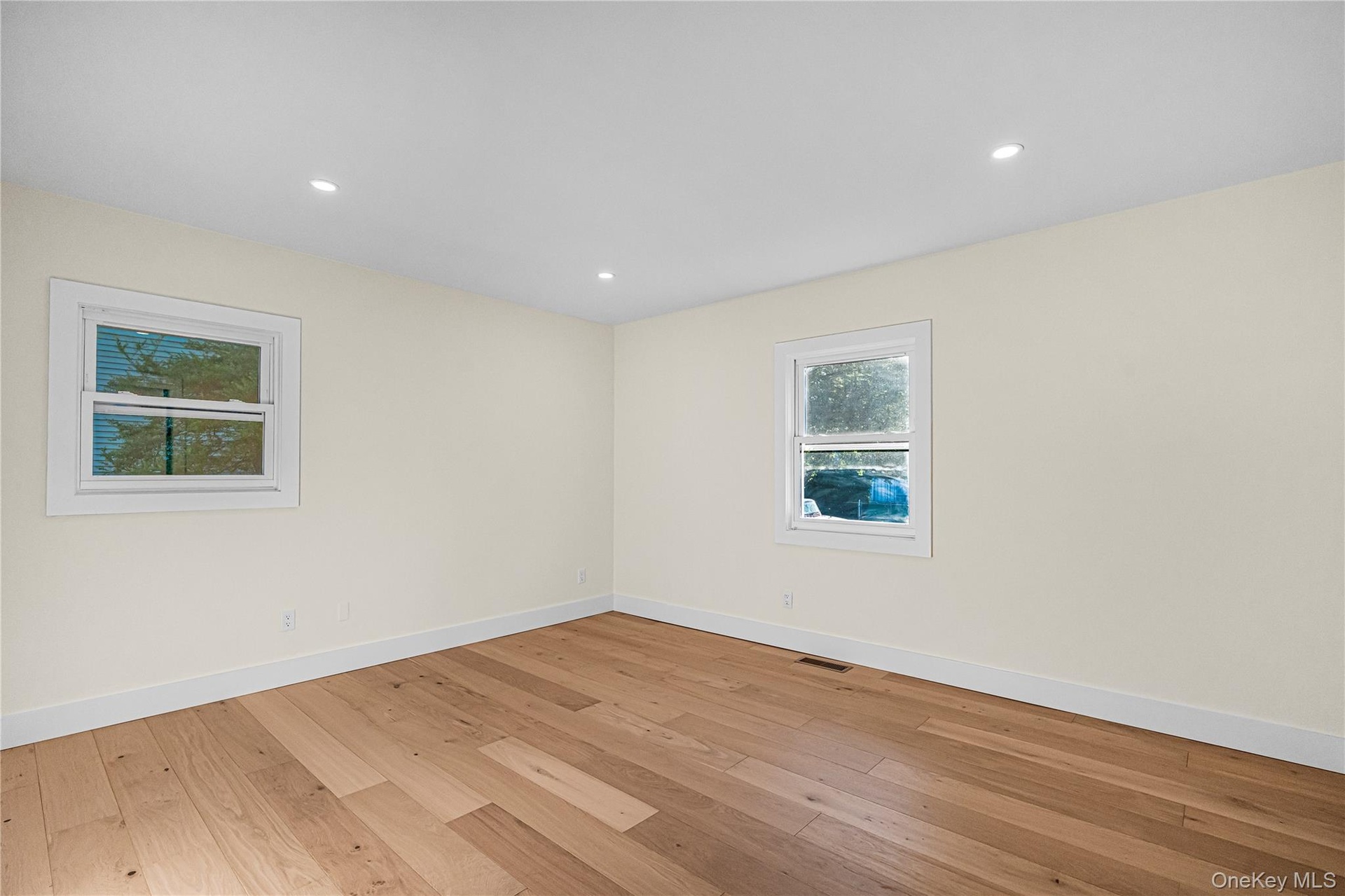 Room featuring warm-toned wood-finish flooring, light-colored walls, and recessed ceiling lighting