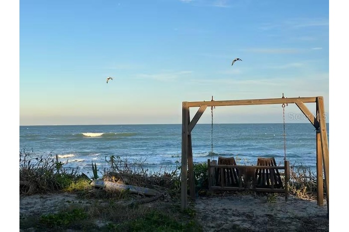 A cozy oceanside swing, gently swaying with the ocean breeze.