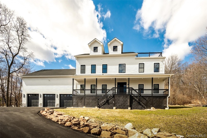 Contemporary Hardie Plank white siding exterior with a multi-level porch, black railings, and a 6-car garage