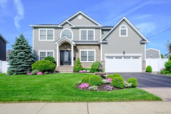 Gray siding exterior with stone accents, a prominent arched window, a two-car garage.