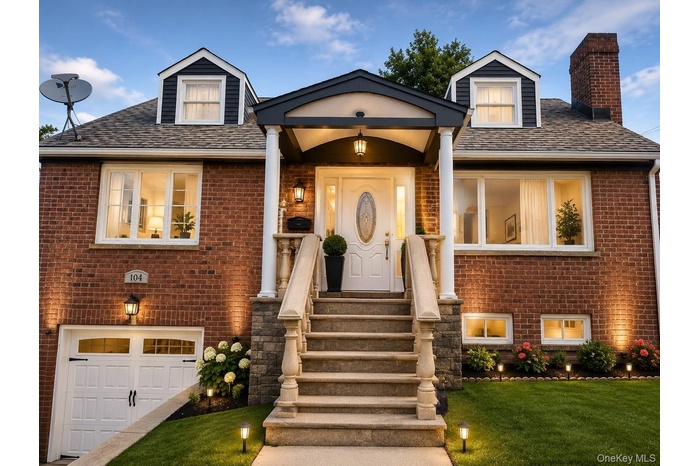 Brick exterior with dormer windows and a covered entry, featuring a stone staircase with balusters